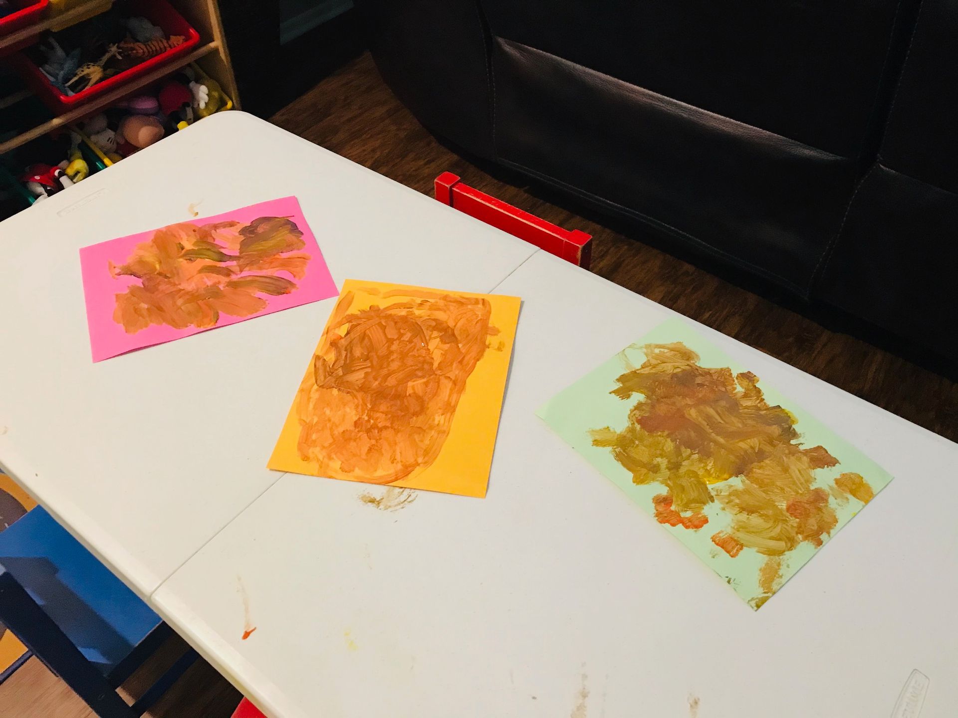 Children and an adult seated around a table, doing crafts with colored paper and pencils in a classroom.