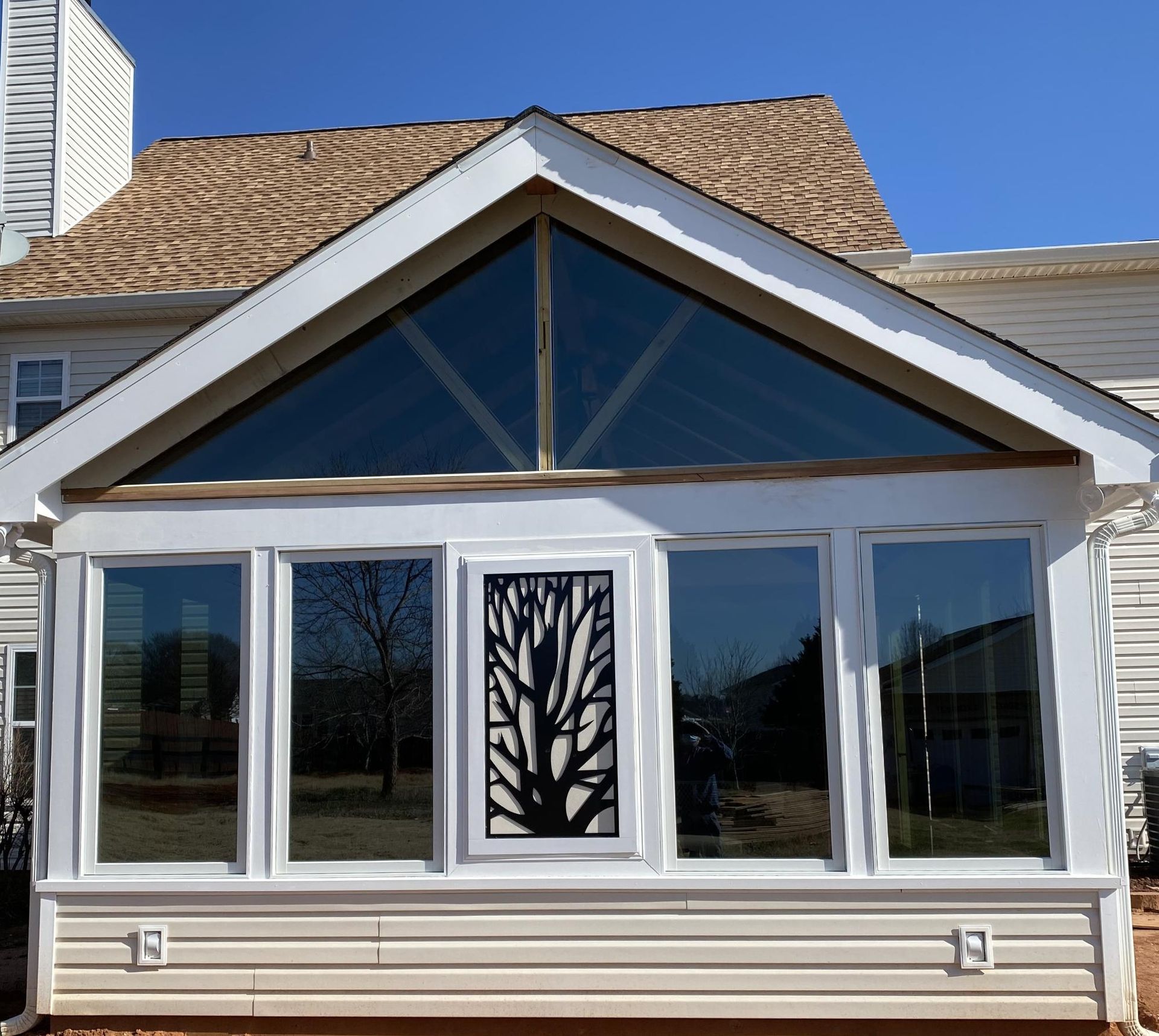 Sunroom with white trim, glass windows, and a decorative tree panel.