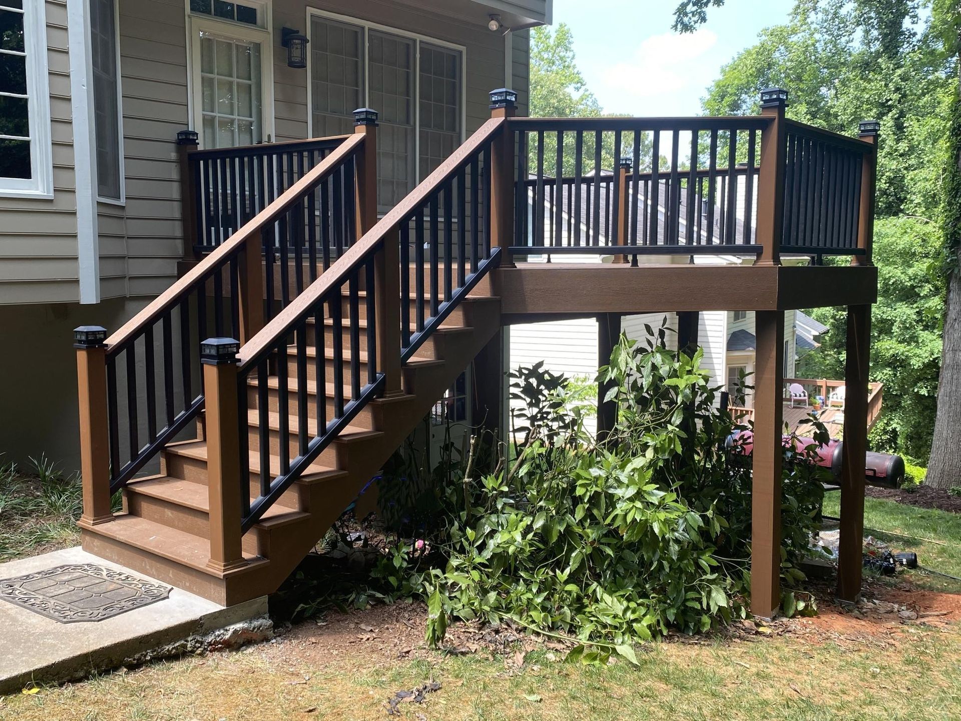 Brown deck with black railing and steps leading up to it.