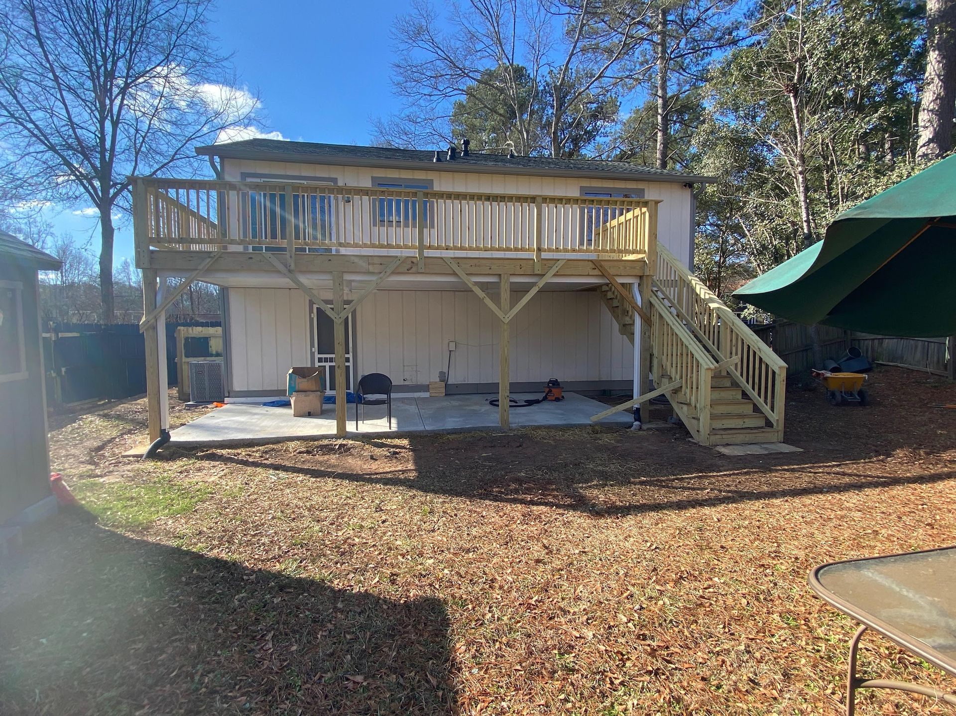 Backyard view of a two-story home with a newly constructed wooden deck and stairs.