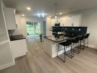 Modern kitchen with white cabinets, black countertops, and a breakfast bar with black stools.