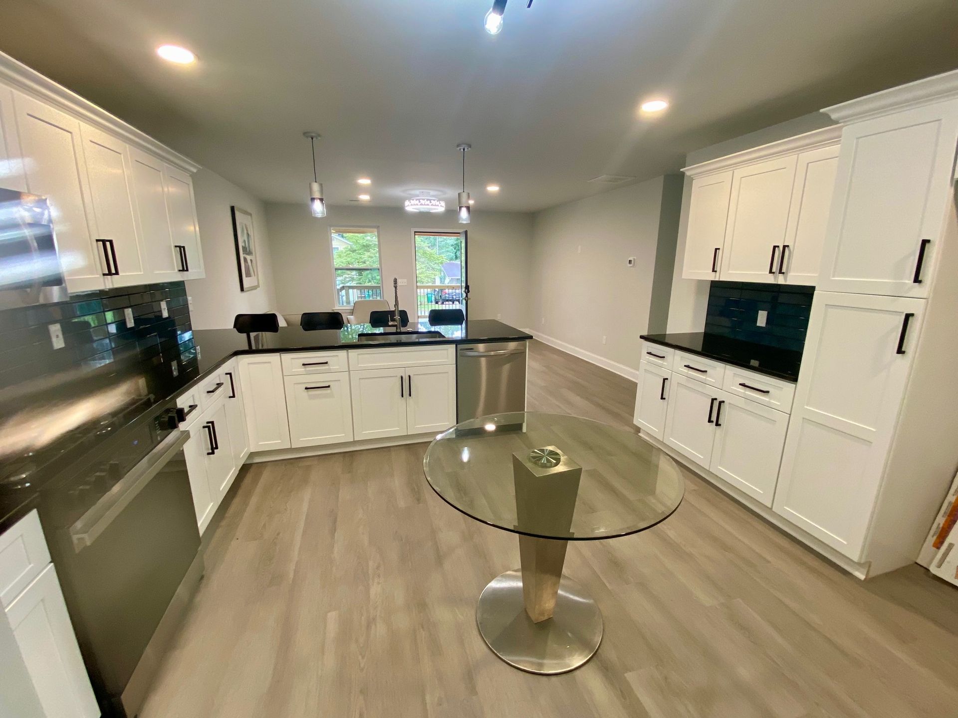 Modern kitchen with white cabinets, stainless steel appliances, and a glass-topped table.