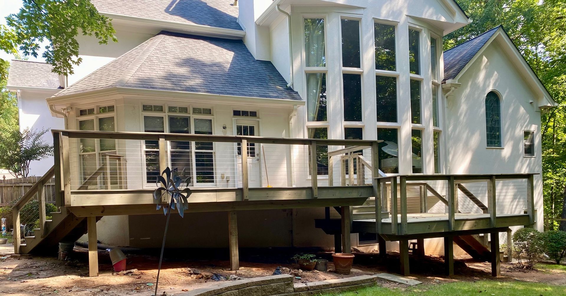 White house with a gray roof and a wooden deck.