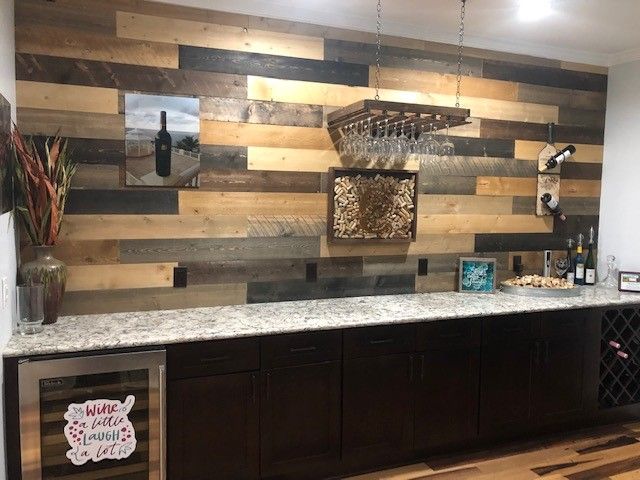 Wine bar with a wooden accent wall, granite countertop, and dark cabinets.