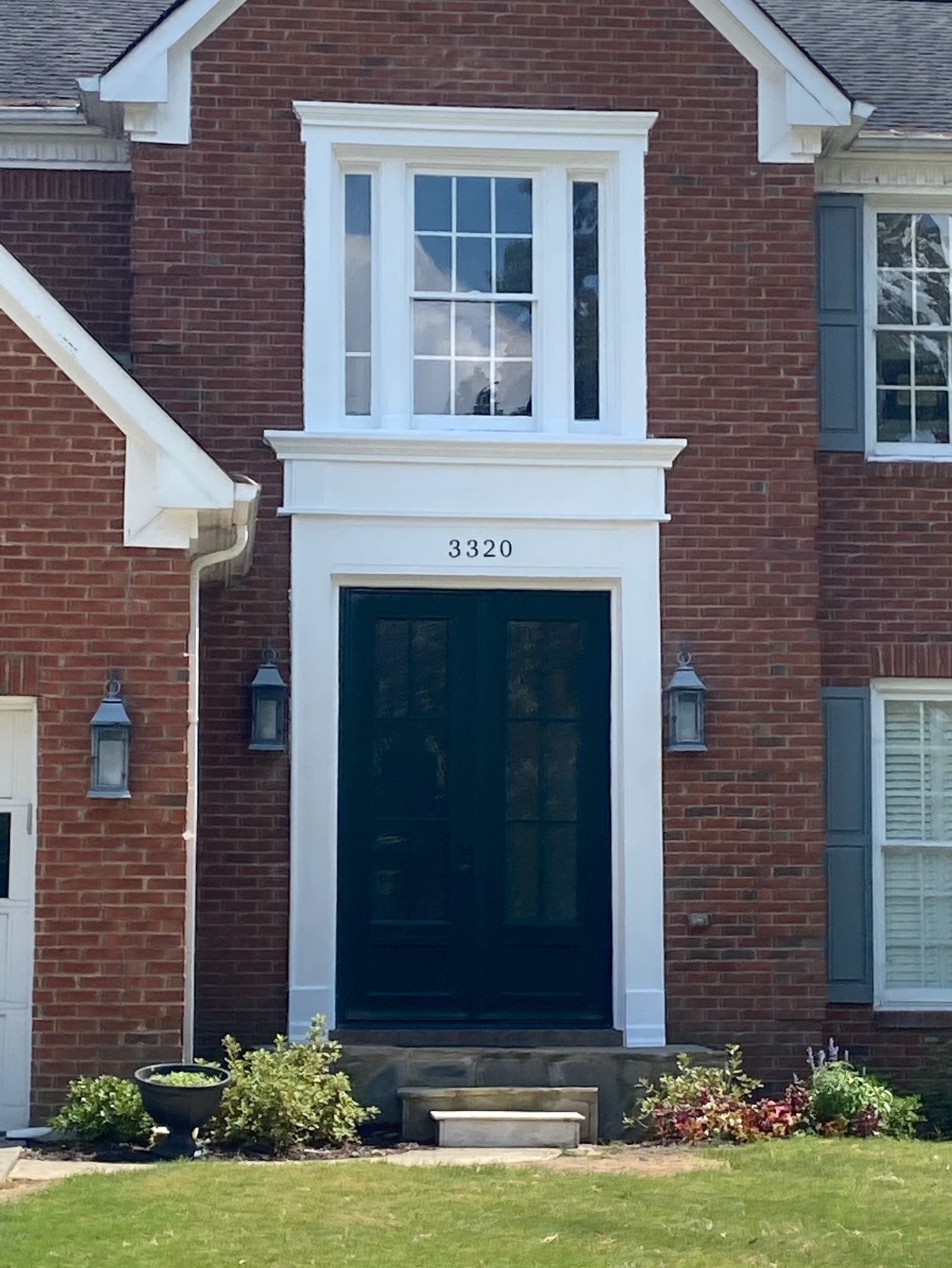Red brick house with a dark blue door, white trim, and a window above.