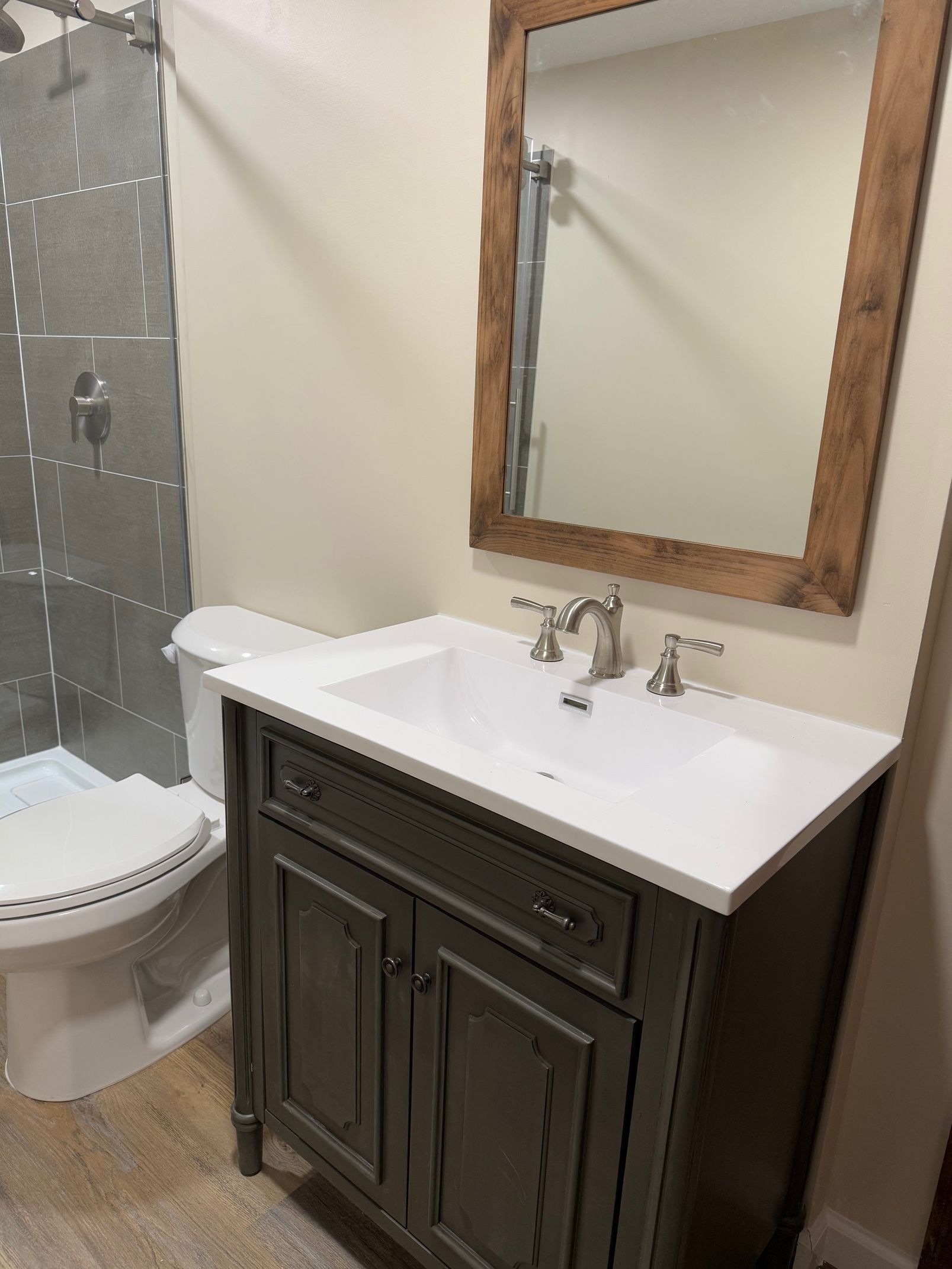 Bathroom with gray vanity, white countertop, rectangular mirror, and a toilet.