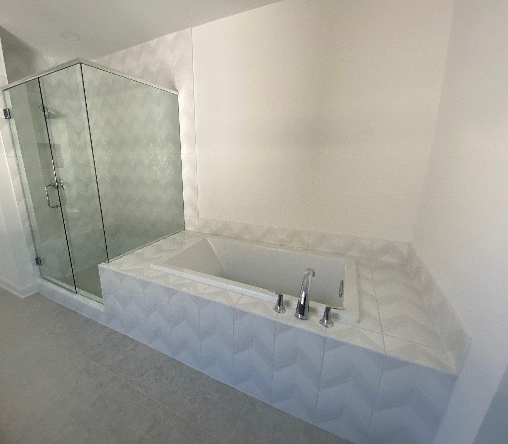 Bathroom with white tile walls, a built-in tub, and a glass shower enclosure.