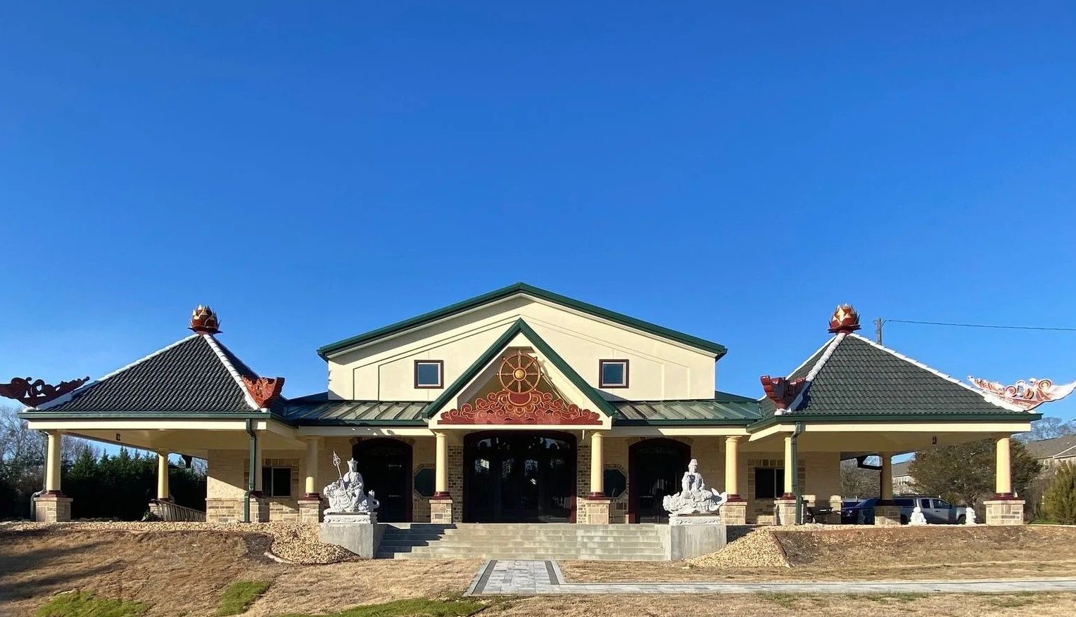 Temple with green tile roof and two side pavilions; blue sky.