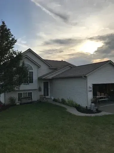 Suburban house with attached garage at sunset, viewed from the front lawn.