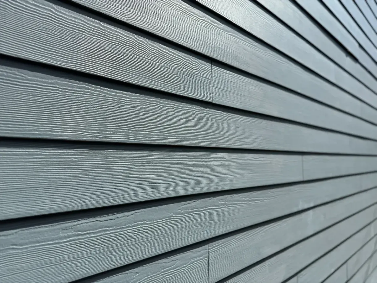 Close-up of gray horizontal siding with diagonal lines and textured wood grain pattern