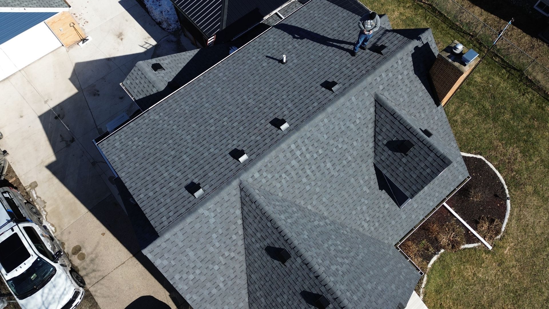 Aerial view of a gray-roofed house with driveway and lawn.