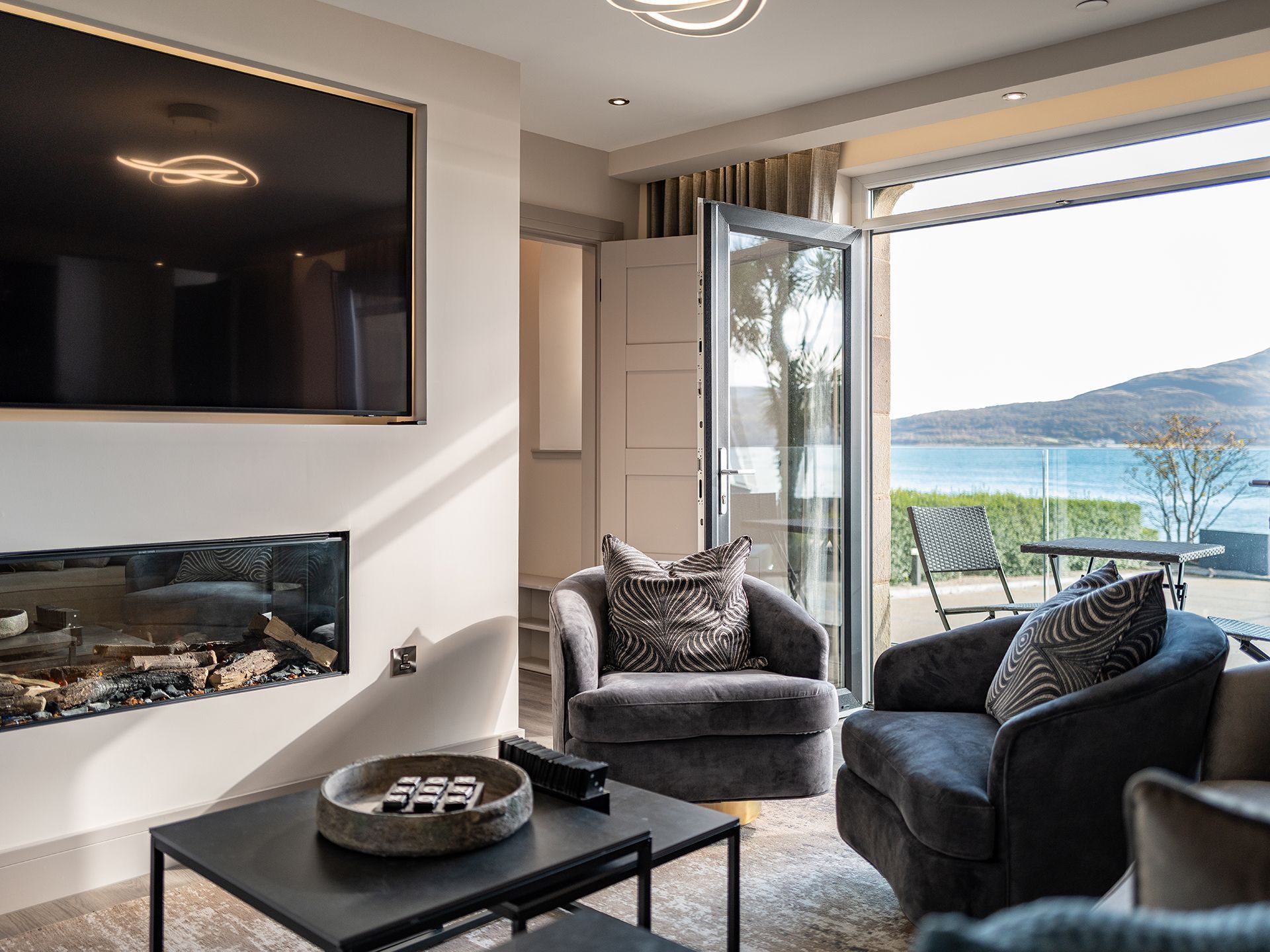 A living room with a fireplace , chairs , and a flat screen tv.