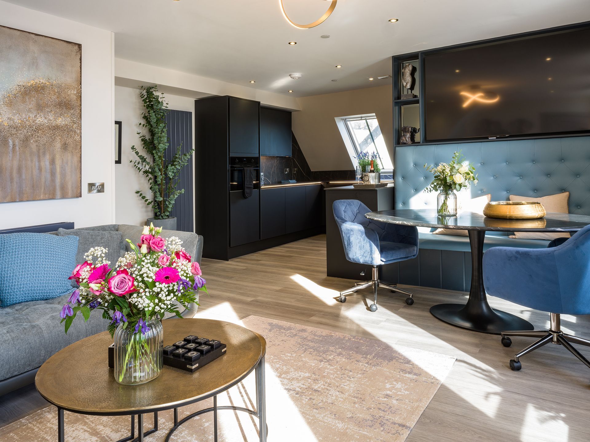 A living room with a couch , table , chairs and a vase of flowers.