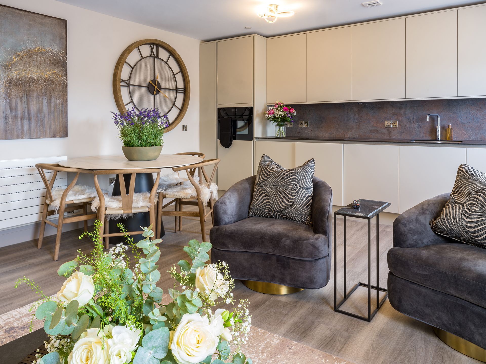 A living room with a clock on the wall and a table and chairs