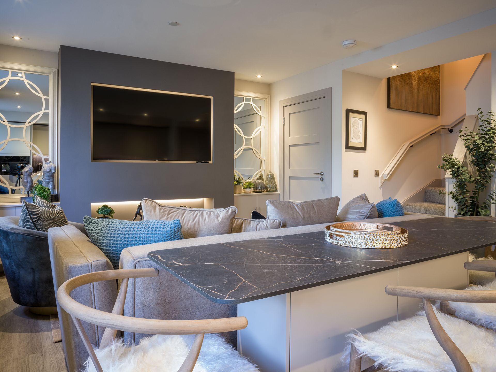 A living room with a couch , chairs and a flat screen tv.