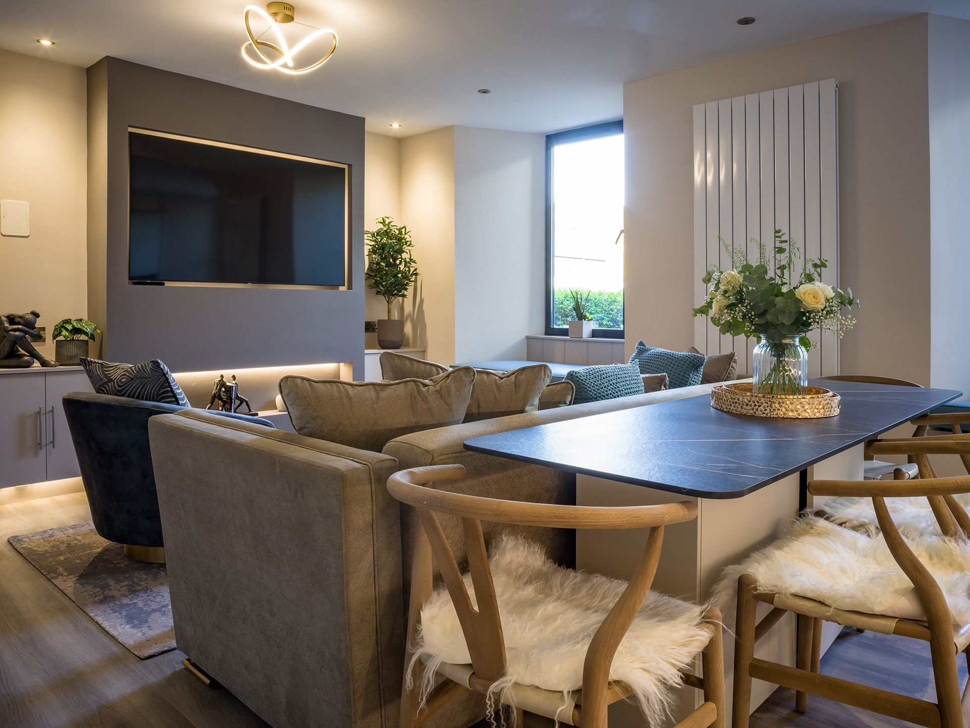 A living room with a couch , chairs , a table and a flat screen tv.