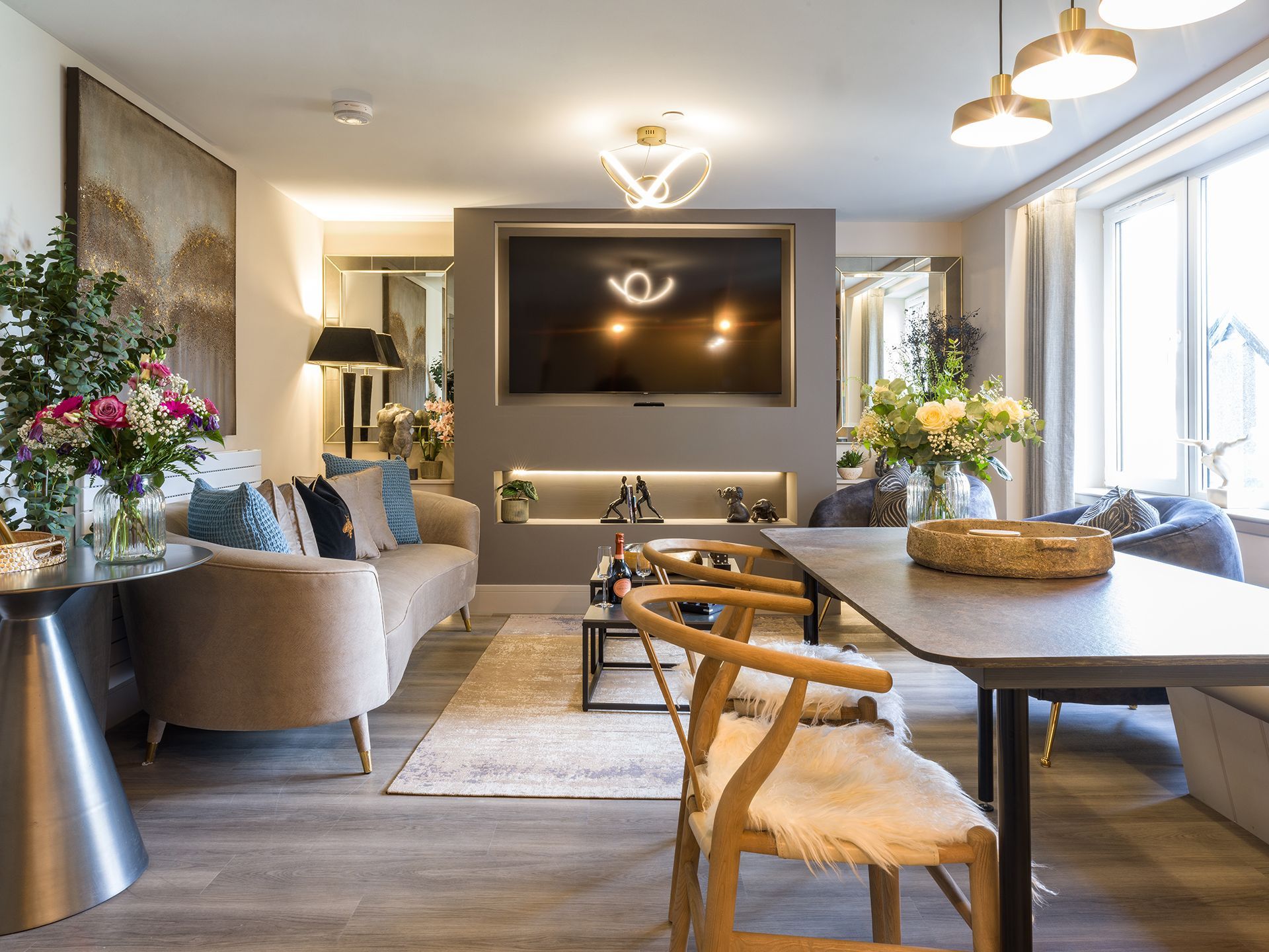 A living room with a couch , table , chairs and a flat screen tv.