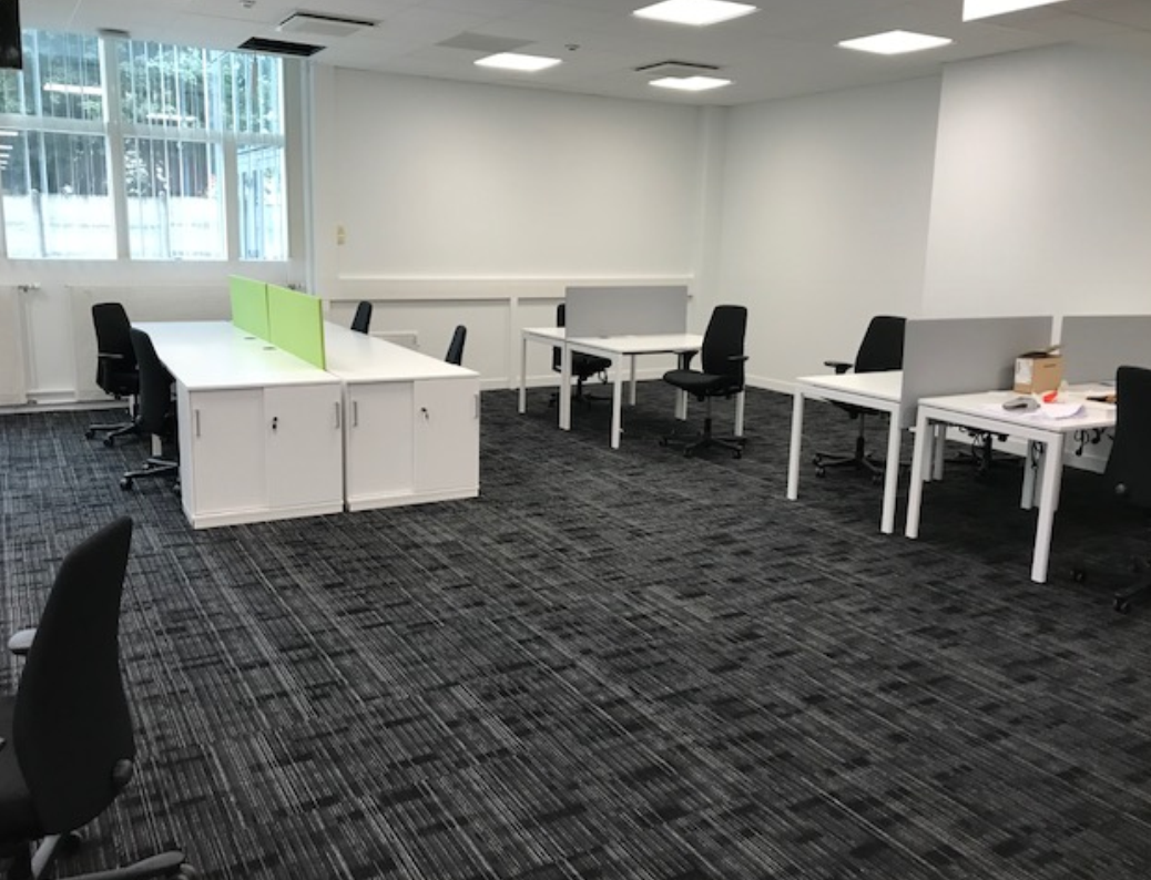 Une grande pièce avec beaucoup de bureaux et de chaises.