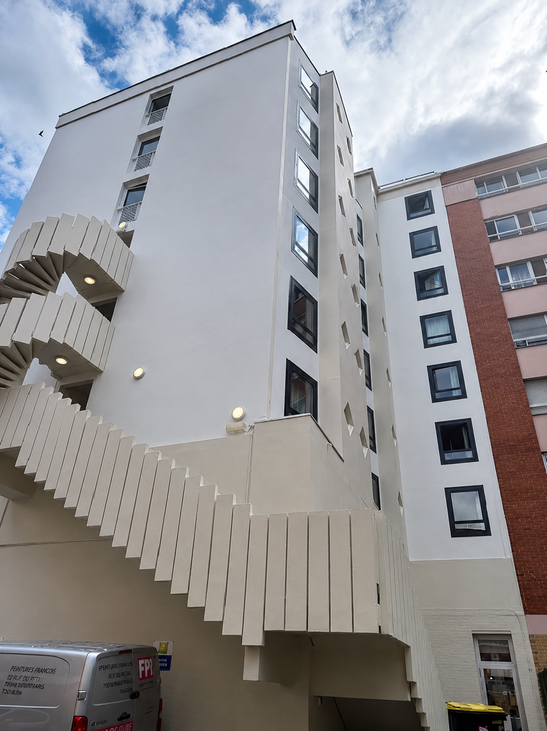 Un grand bâtiment avec beaucoup de fenêtres et de balcons par temps nuageux.