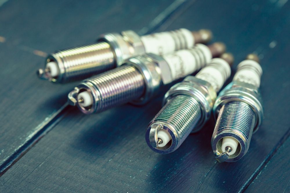 Four Spark Plugs Are Sitting on a Wooden Table — Coffs Harbour Bearing Centre in Coffs Harbour, NSW