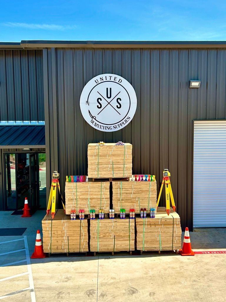 Stacked wooden crates and cones outside a building with a U.S. logo sign above the entrance.