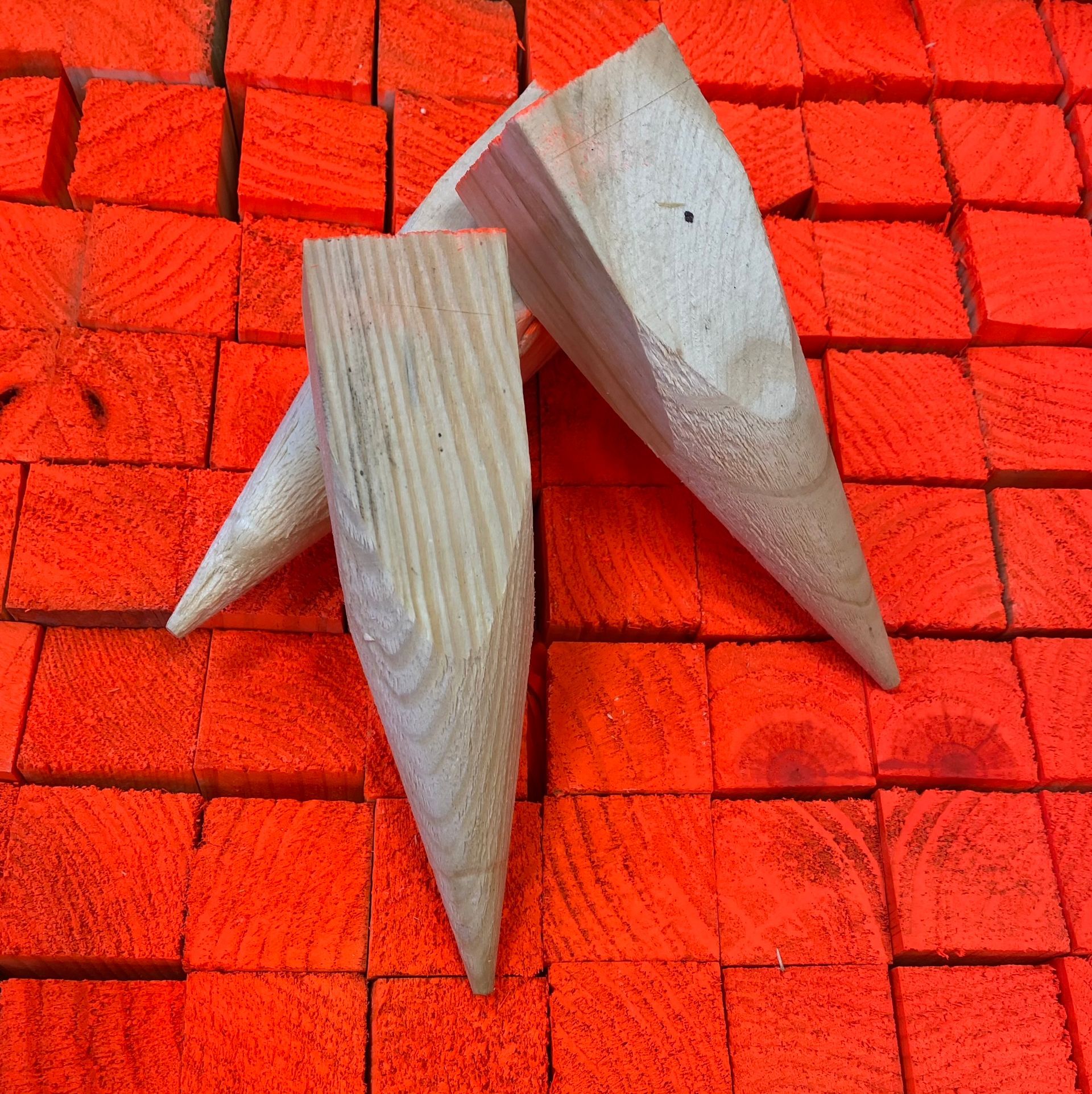 Three wooden clothespins on a bright red tiled surface