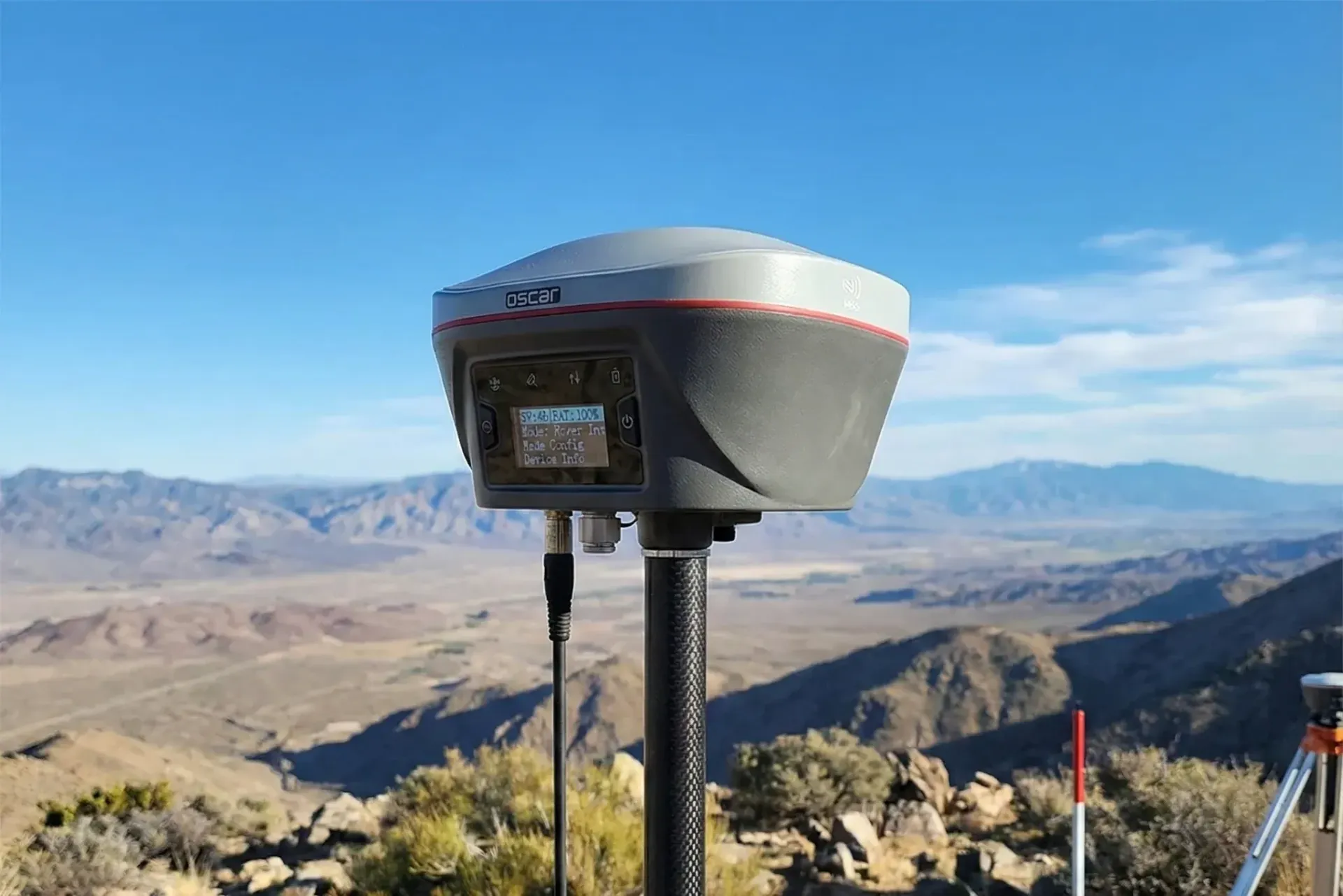 Summit telescope overlooking a rocky desert valley under a clear blue sky