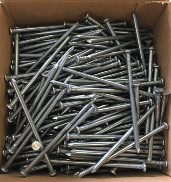 Box filled with loose silver nails, viewed from above