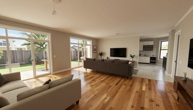 Bright open-plan living room with hardwood floors, beige sofa, TV, and large windows overlooking a yard