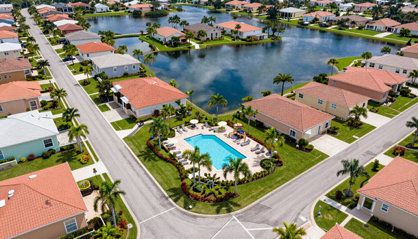 Aerial view of a suburban neighborhood with a swimming pool and large lake surrounded by homes.