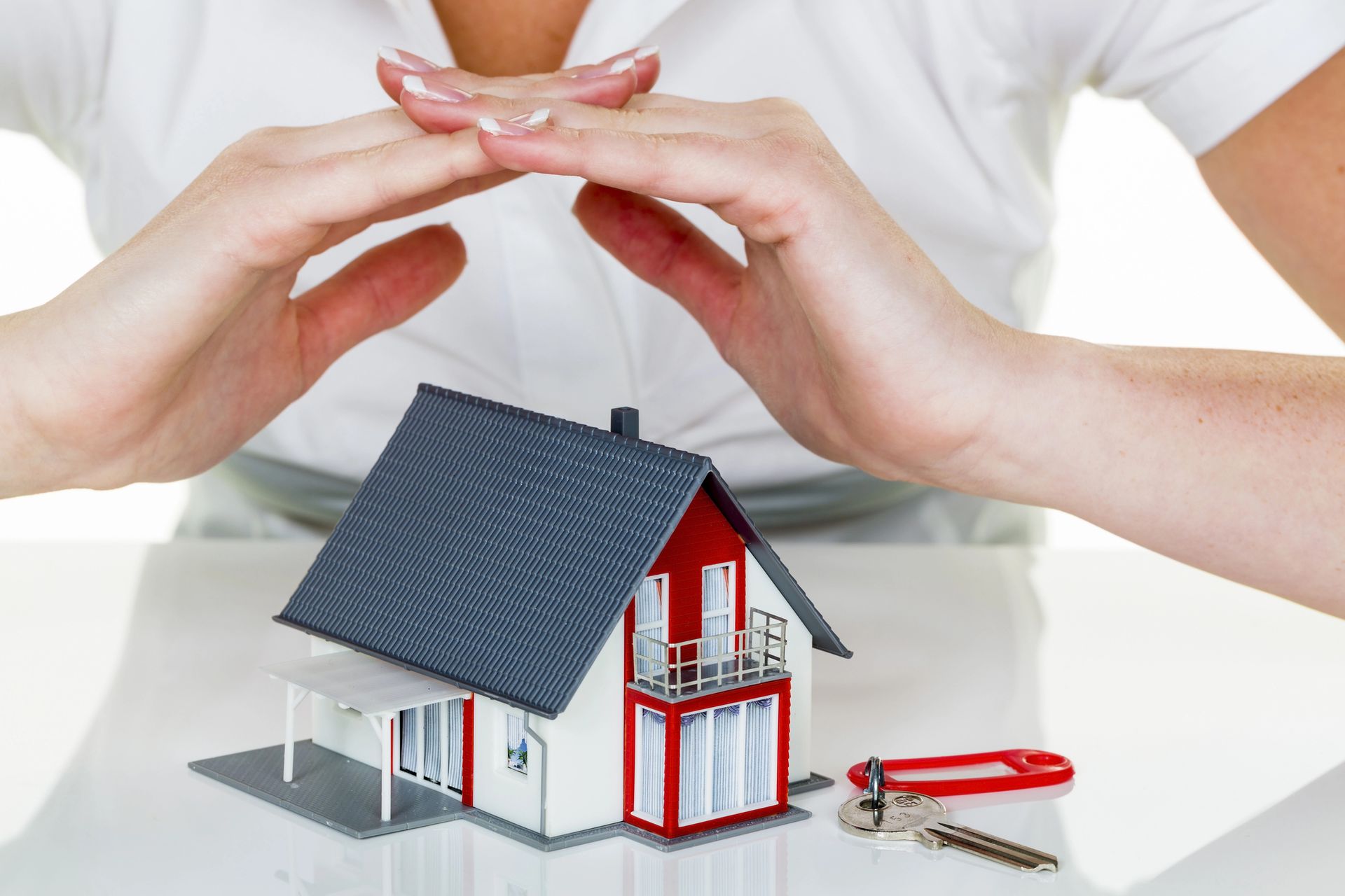 Unas manos forman un refugio protector sobre una pequeña maqueta 