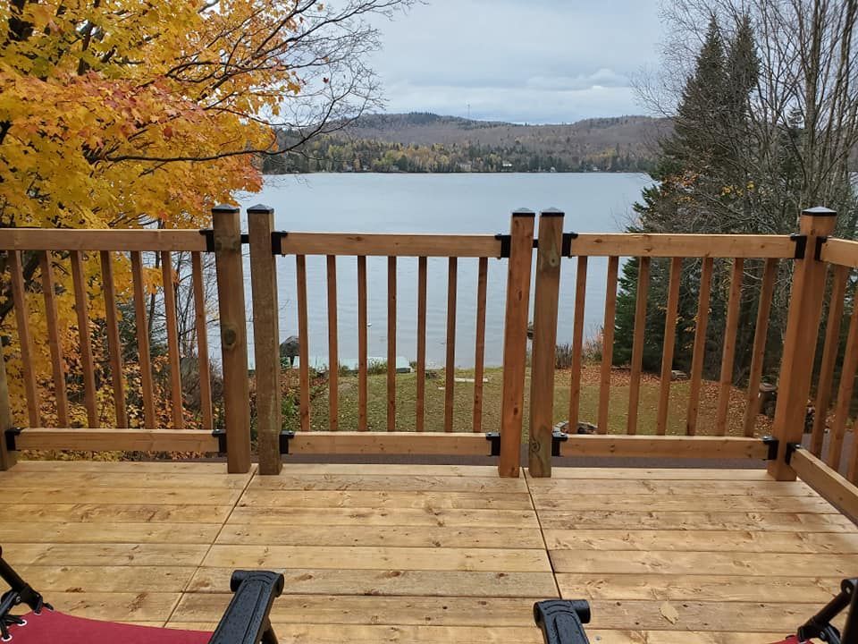 Terrasse en bois surplombant un lac, entourée de feuillages d'automne.