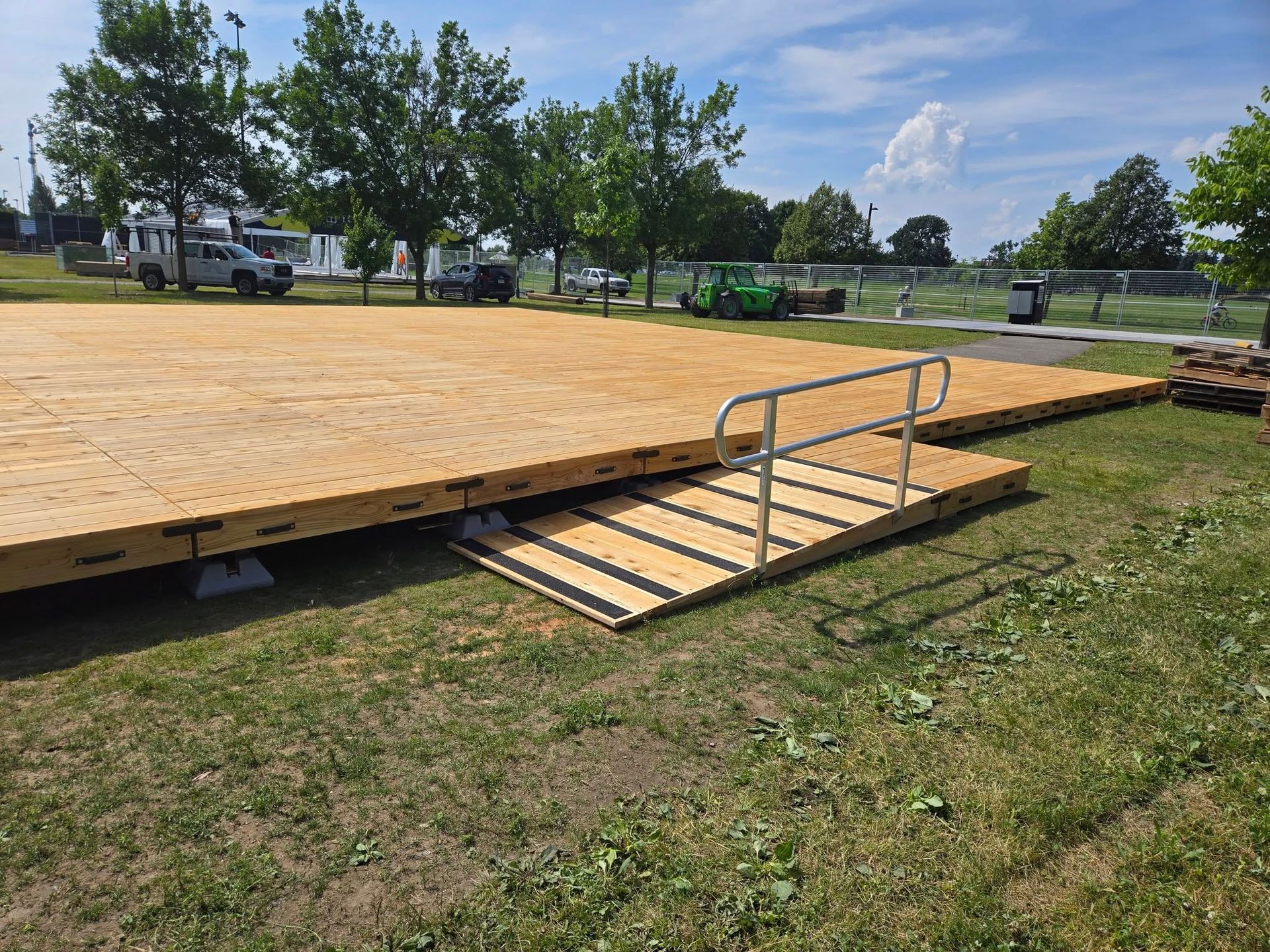 Plateforme en bois avec rampe et main courante sur gazon, en extérieur.