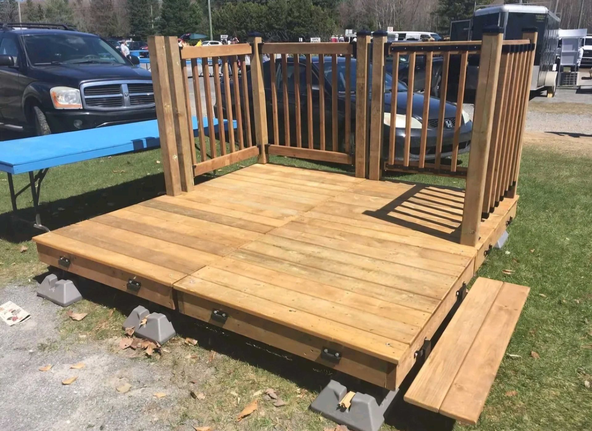 Terrasse en bois avec rambarde sur blocs de béton gris, située à l'extérieur.