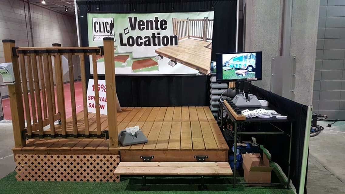 Présentoir de terrasse en bois lors d'un salon professionnel, avec signalétique et petit téléviseur diffusant une vidéo associée.