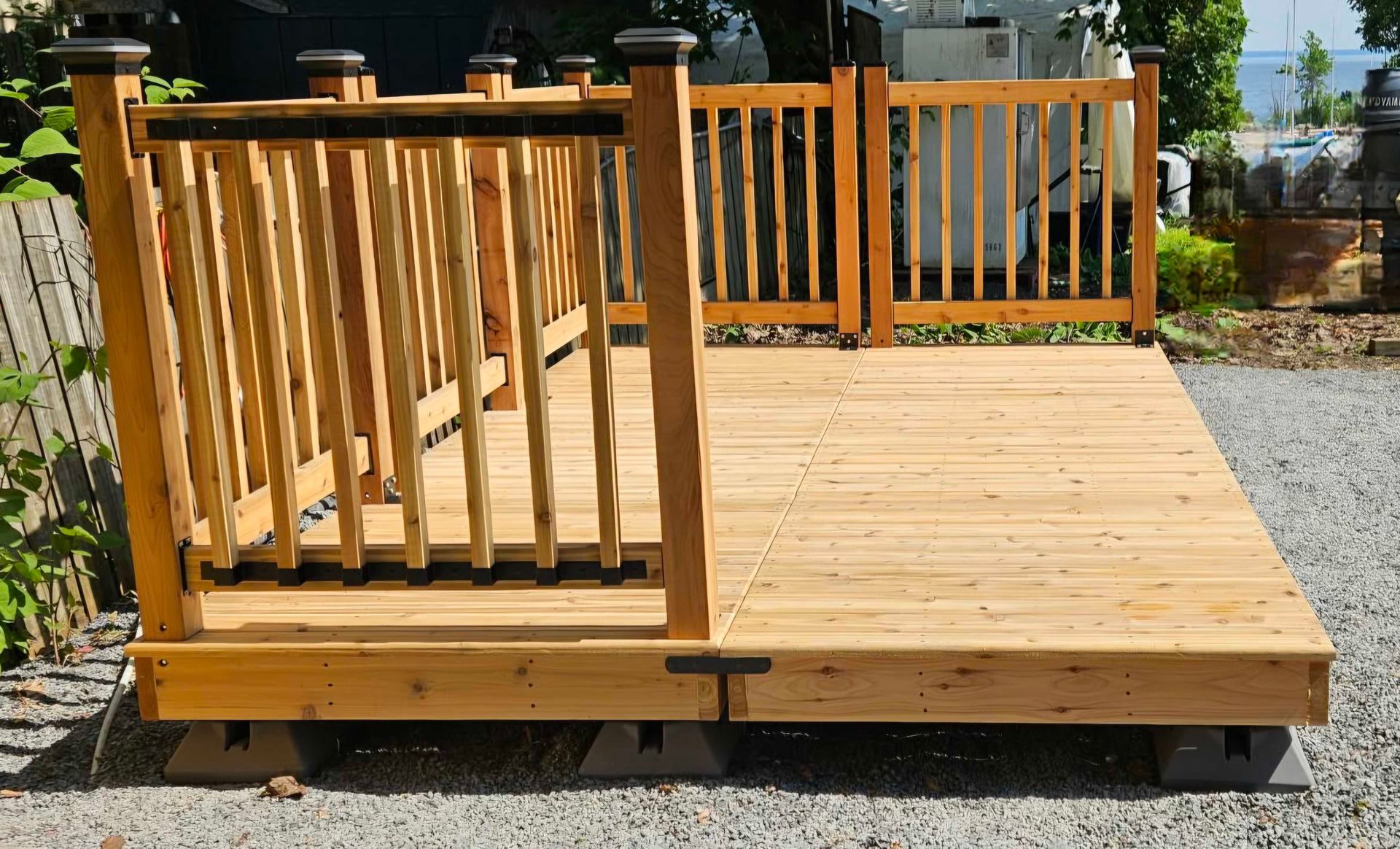 Terrasse en bois avec rambarde et portail, installée sur des blocs, en extérieur.