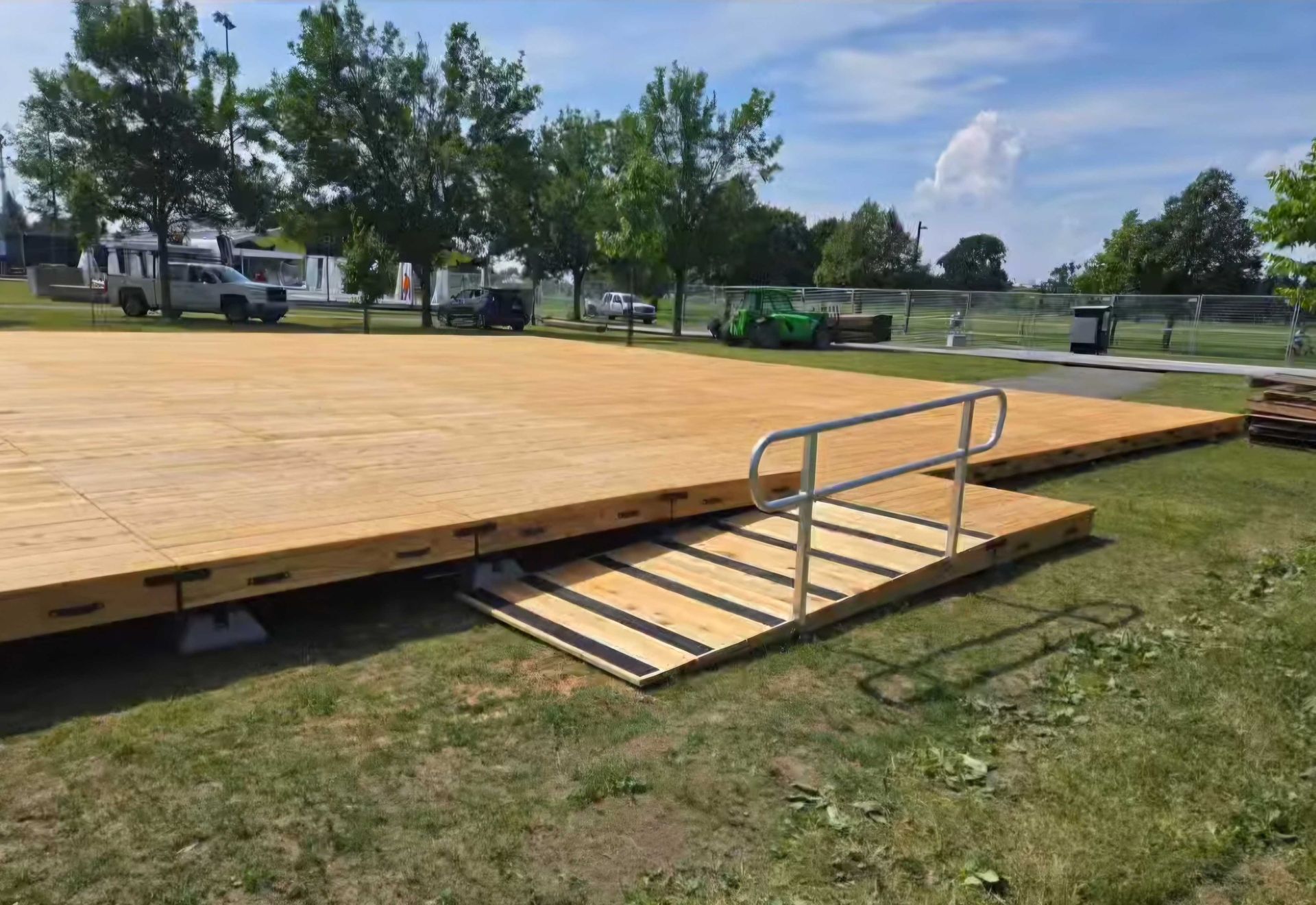 Plateforme en bois avec rampe et main courante sur gazon, en extérieur.