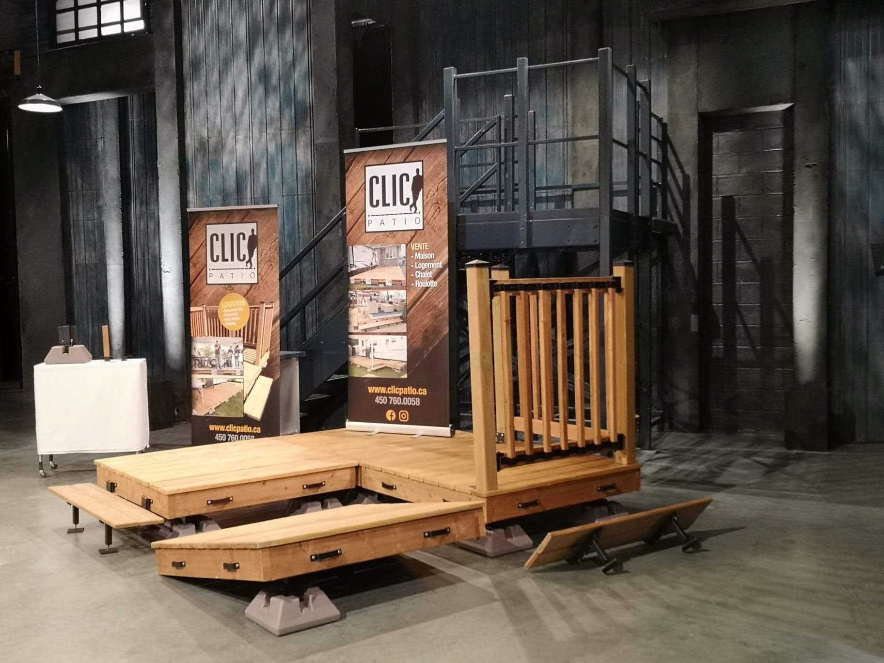 Scène en bois avec rampes et escaliers, à l'intérieur avec des bannières « CLIC ».