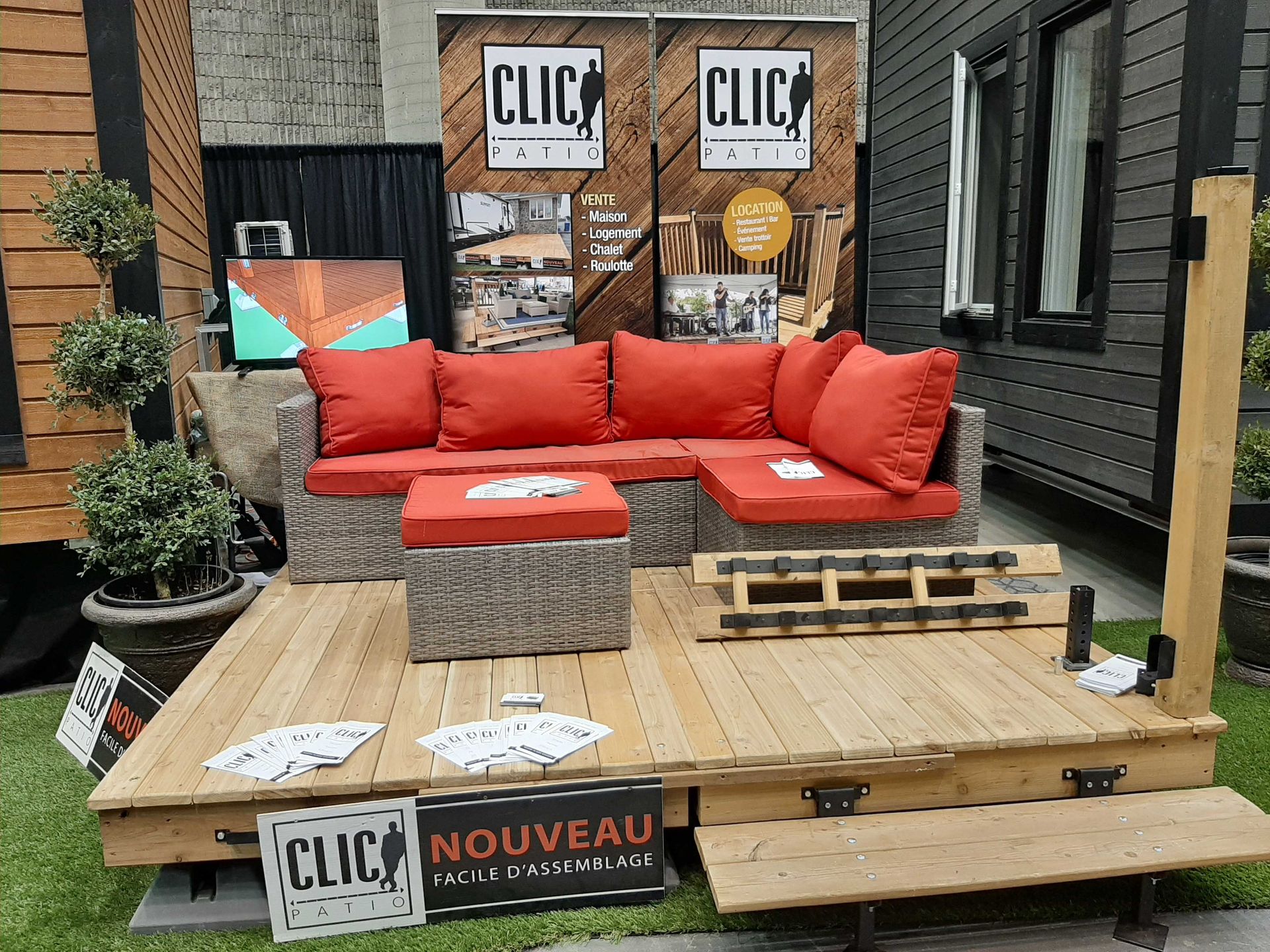 Aménagement extérieur avec canapé d'angle, terrasse en bois et enseigne « CLIC ».