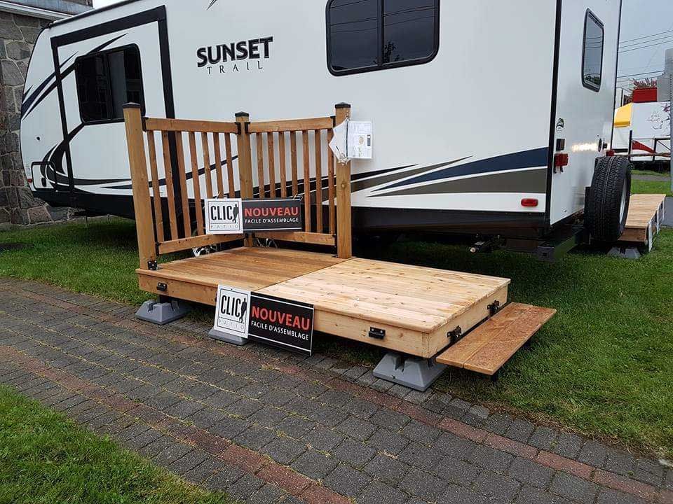 Plateforme en bois pour camping-car avec rampe et rambarde devant le véhicule.