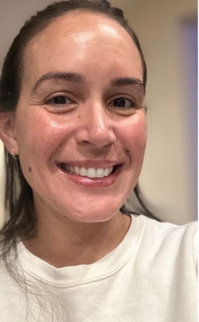 A woman is smiling for the camera while wearing a white shirt.