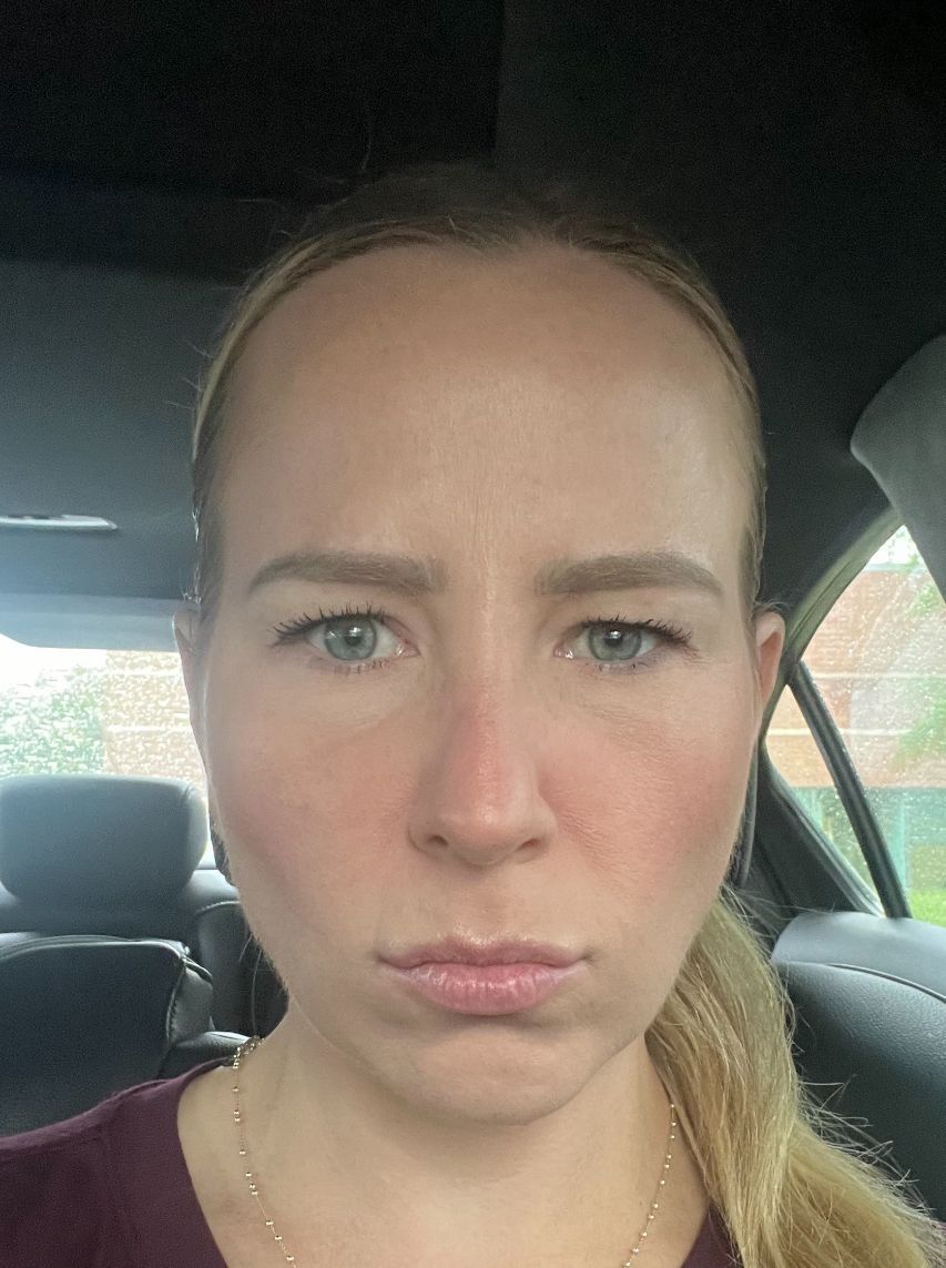 A woman is sitting in the back seat of a car making a funny face.