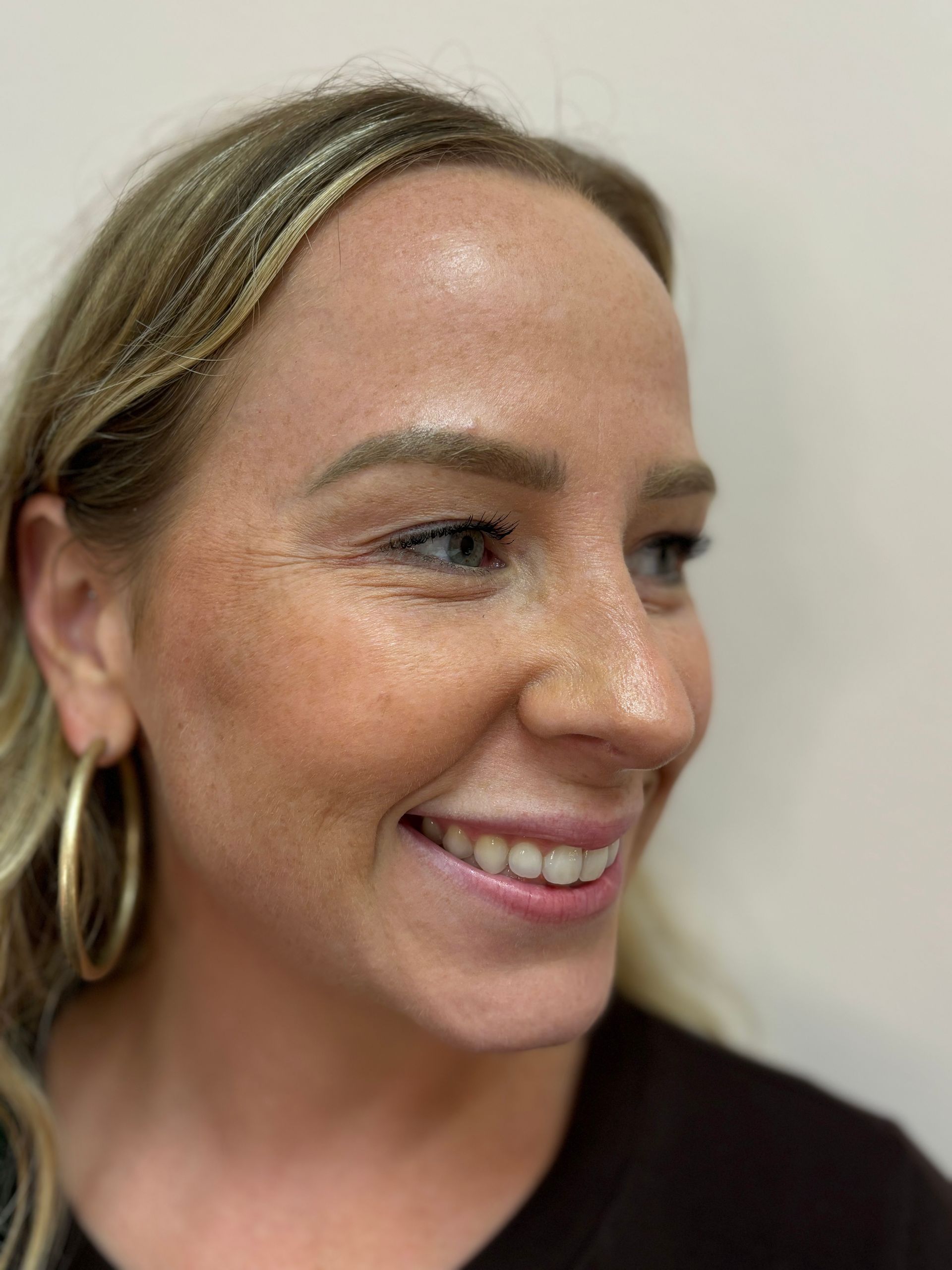 A close up of a woman 's face wearing hoop earrings and smiling.