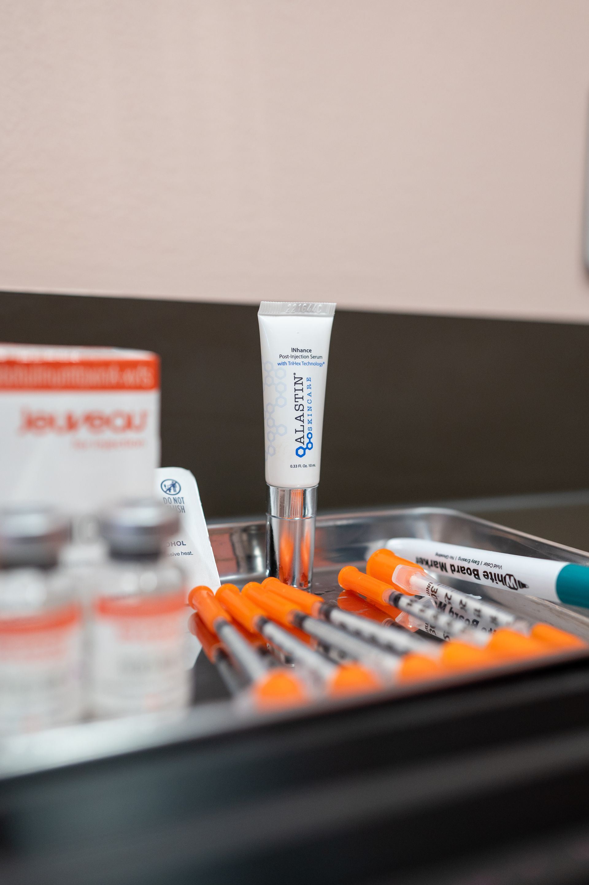 A tray of syringes and a tube of cream on a table.