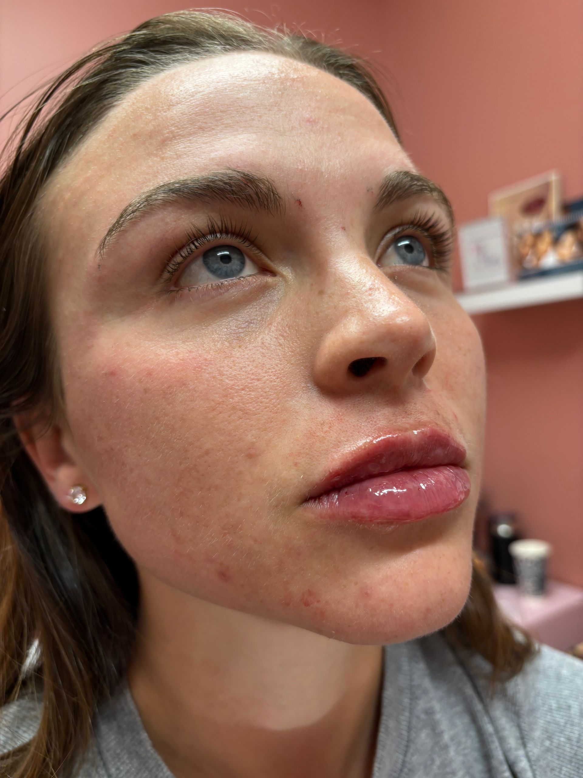 A close up of a woman 's face with a pink wall in the background.