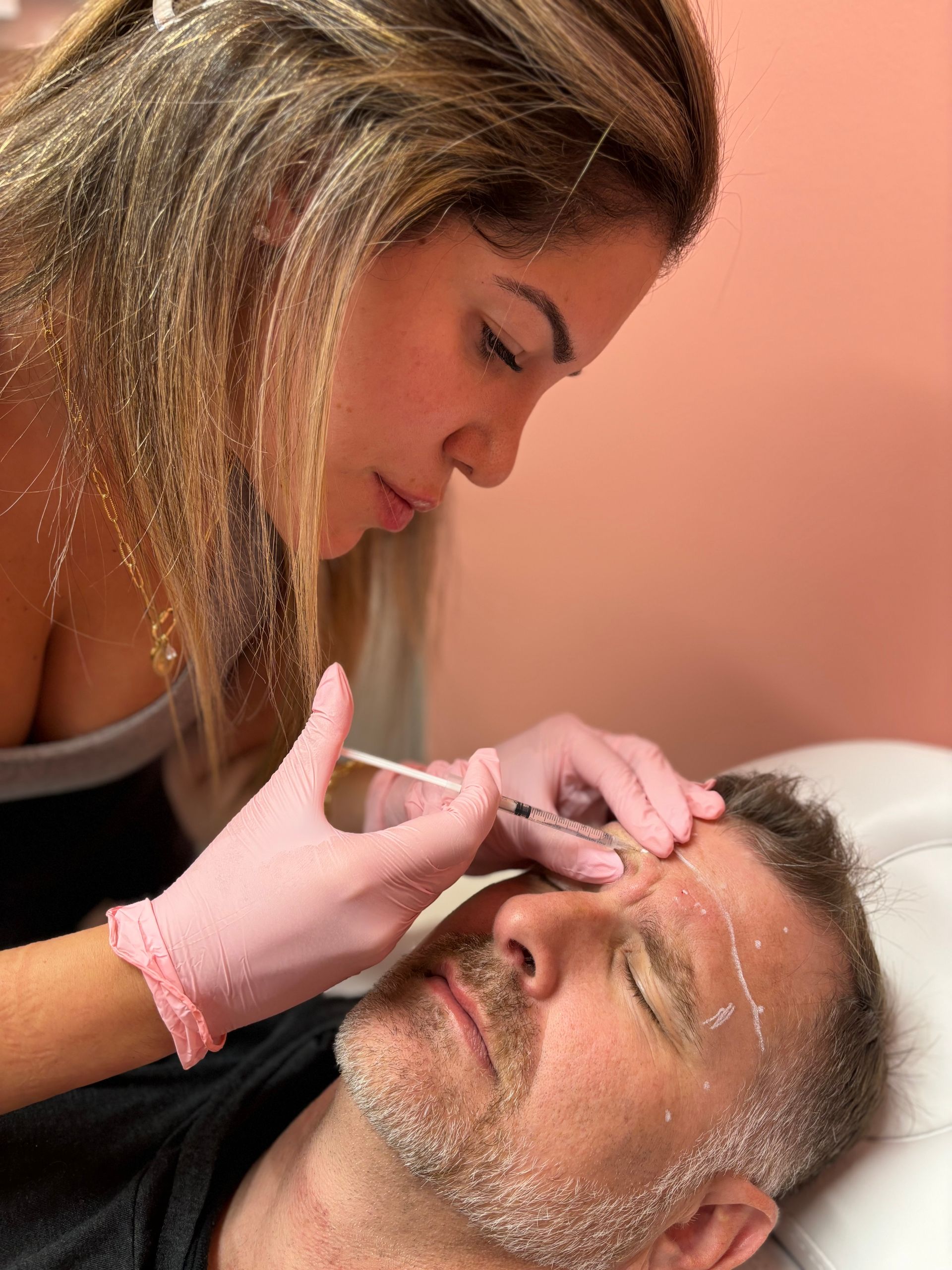 A woman is giving a man a botox injection in his forehead.