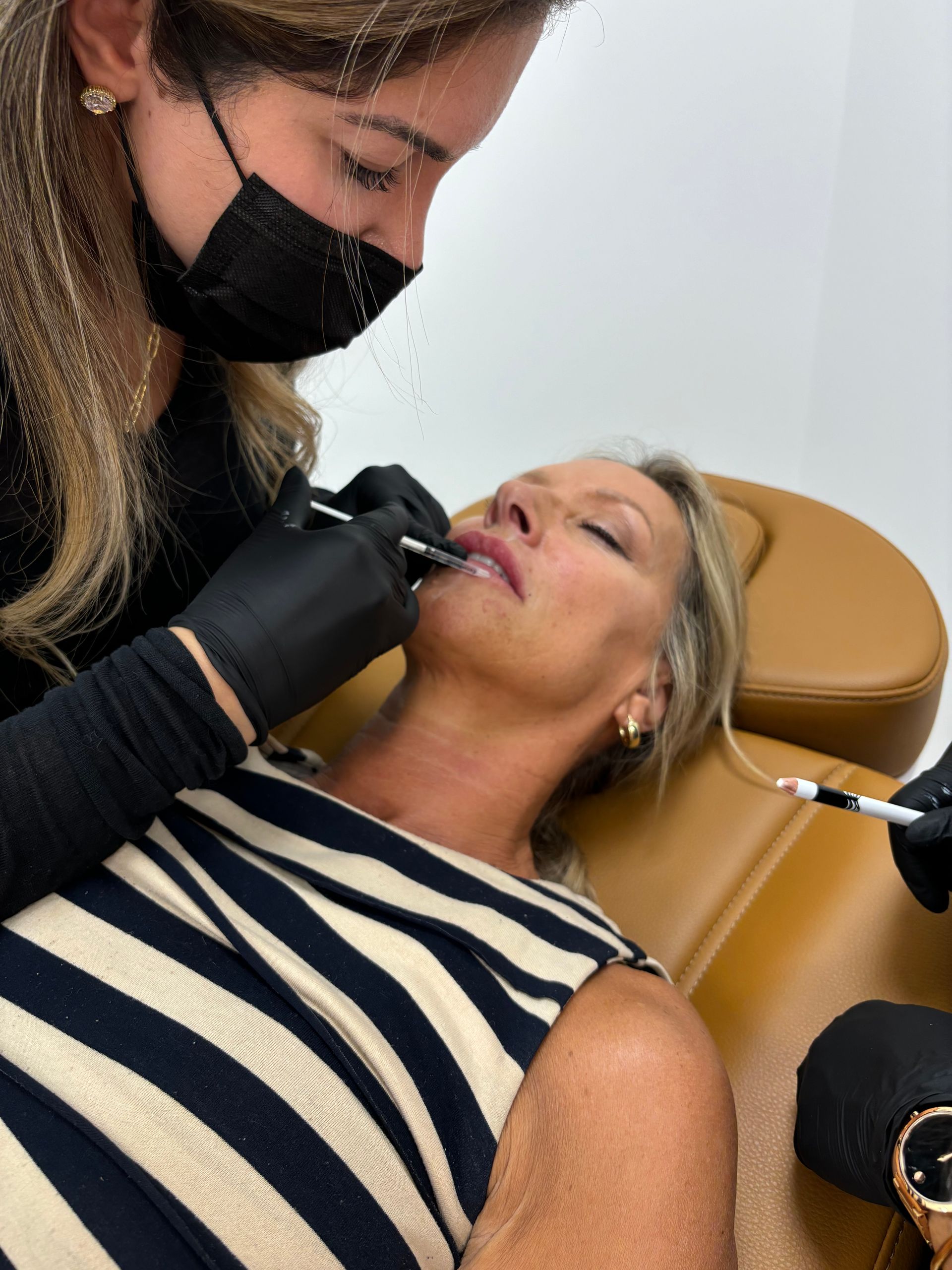 A woman is getting a botox injection in her lips.