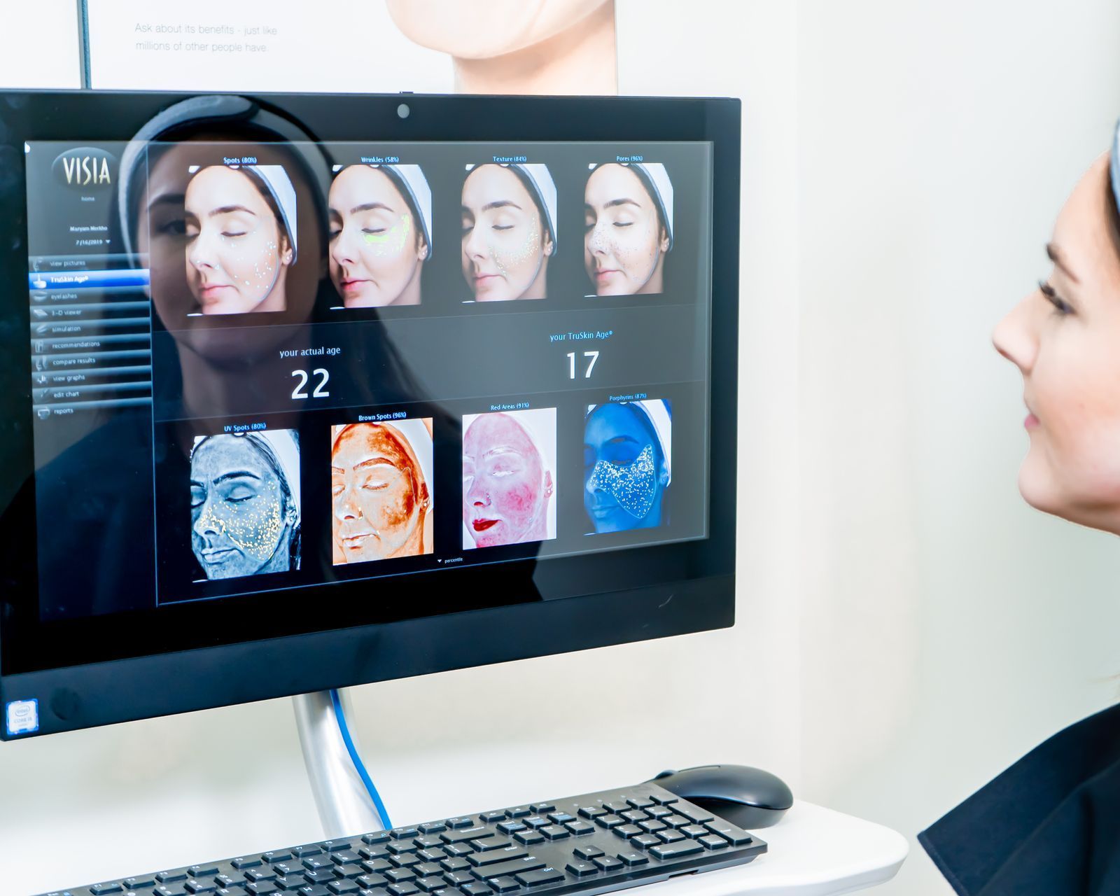 A woman is looking at her face on a computer screen.
