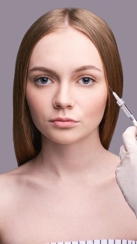 A woman is getting a botox injection in her forehead.
