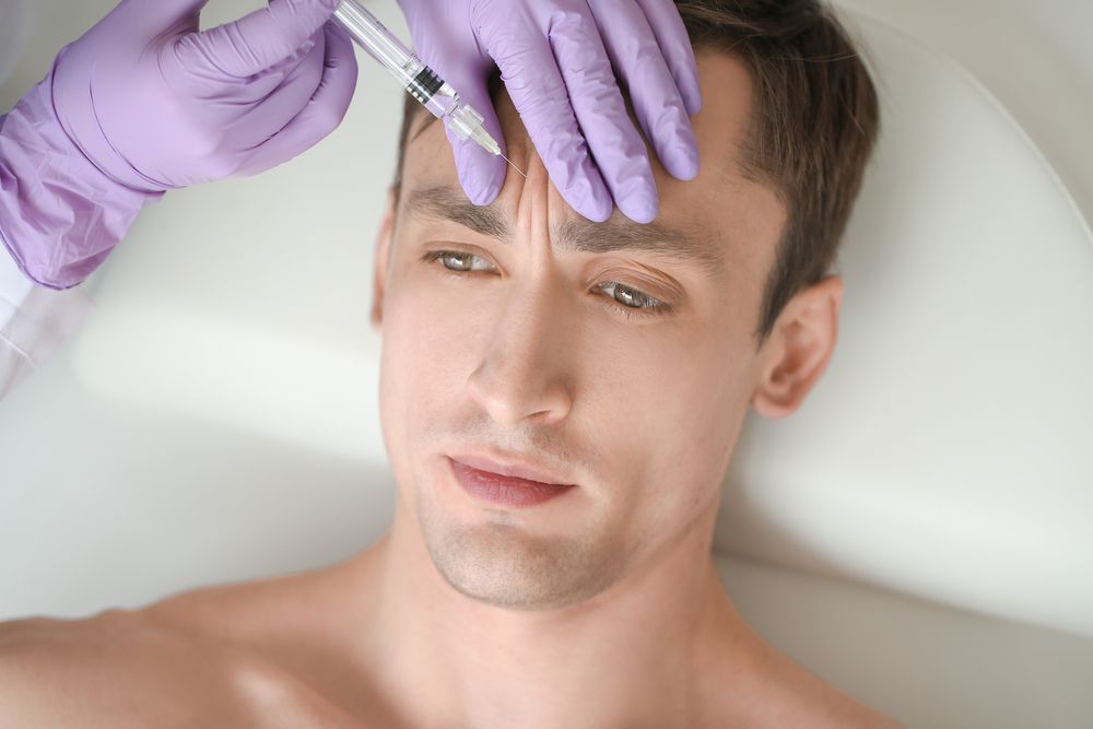 A woman is getting a botox injection in her forehead.